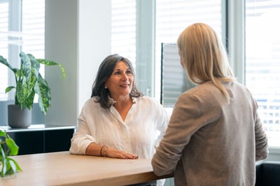 Zwei Frauen im persönlichen Gespräch am Empfang eines modernen Büros.