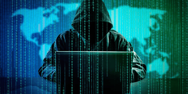 eine Person mit Kapuzenpulli am Laptop und im Vordergrund Binärzahlen