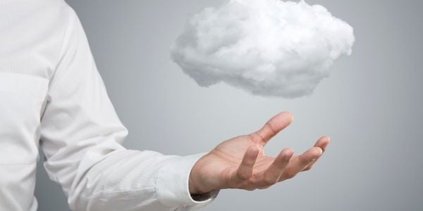 Cloud Computing Symbolbild – Geschäftsmann hält symbolische Datenwolke in der Hand vor grauem Hintergrund