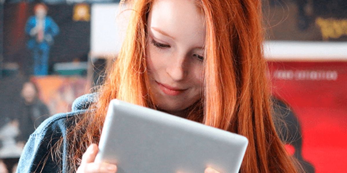 Junges Mädchen mit roten Haaren nutzt Tablet für digitales Lernen oder Freizeit