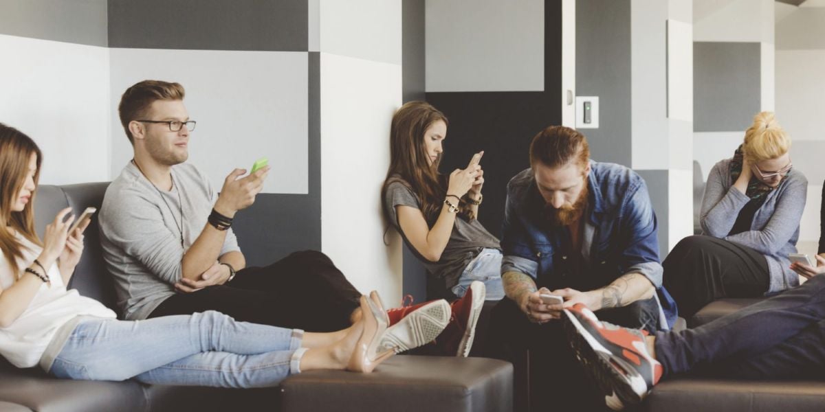 Smartphone-Nutzung bei jungen Erwachsenen – Gruppe vertieft in Mobilgeräte in moderner Lounge