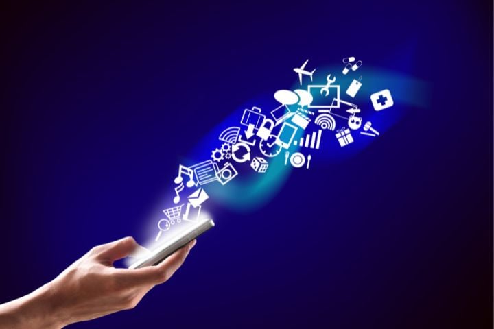 Eine Hand die ein Telefon hält und daraus symbolisch Apps herausfliegen.