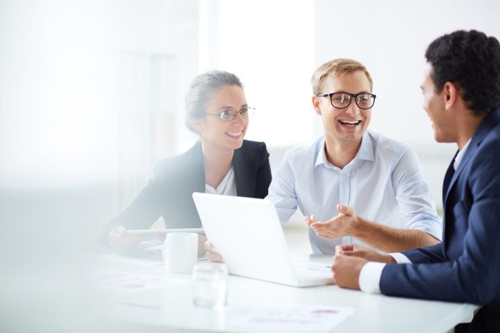 Drei Personen die miteinander eine Besprechung halten.