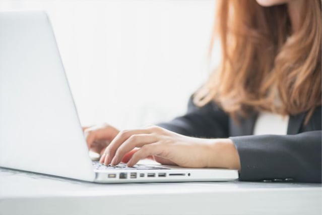 Geschäftsfrau arbeitet konzentriert an einem Laptop, möglicherweise mit 'Sage 100' für Rechnungswesen, in einem Büro in der Schweiz.