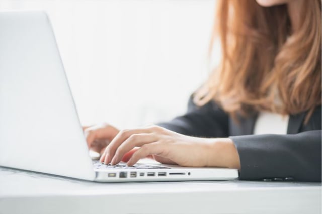 Geschäftsfrau arbeitet konzentriert an einem Laptop, möglicherweise mit 'Sage 100' für Rechnungswesen, in einem Büro in der Schweiz.