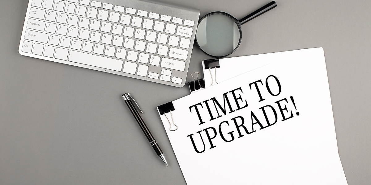 IT-Upgrade Hinweis auf Schreibtisch mit Tastatur, Lupe und Notiz „Time to Upgrade“