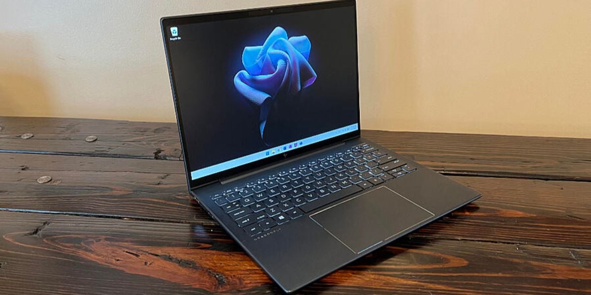 Windows 11 Laptop auf Holztisch – modernes Ultrabook mit Startbildschirm und stilisiertem Hintergrundbild