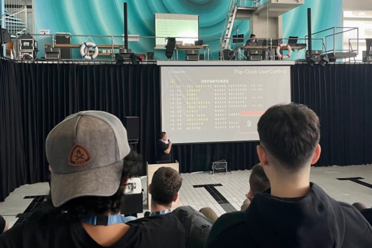 Zuhörerschaft bei einer Präsentation auf dem 'Young Talents Hackathon' in der Schweiz, mit Fokus auf einem Vortragenden, der eine Flip-Clock UserControl demonstriert.